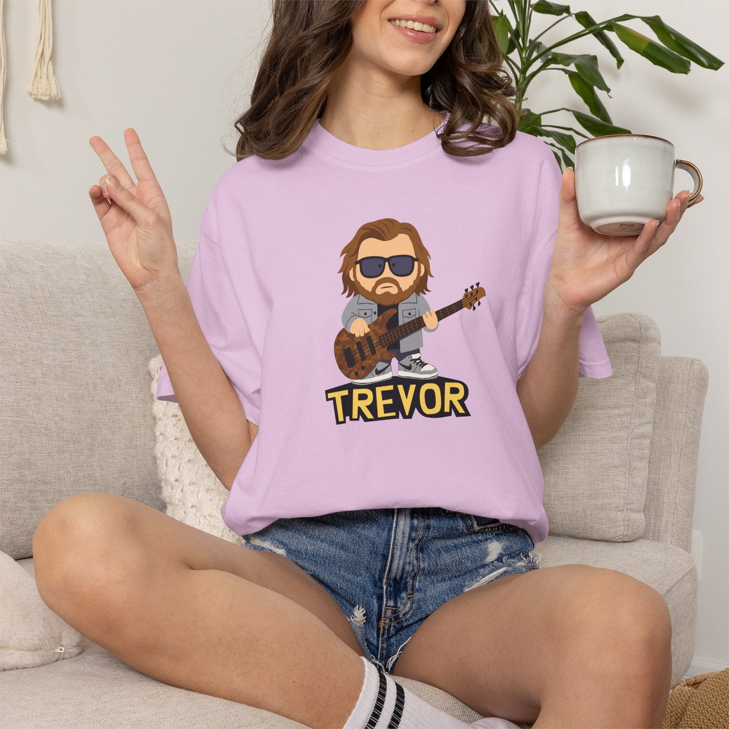 Person wearing a Orchid t-shirt with a graphic design holding a mug.